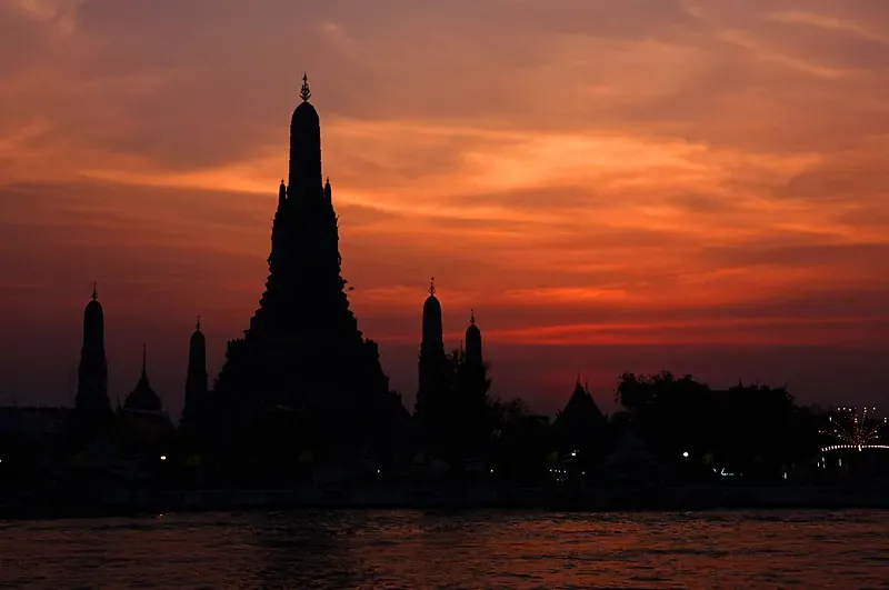 Wat Arun beside the Chao Phraya River at sunset in Bangkok